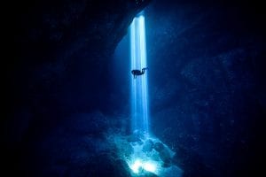 light shaft in ocean cavern with diver